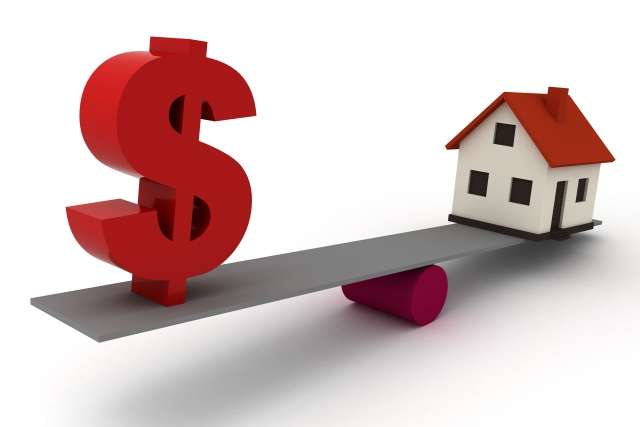 Red dollar sign balanced on a seesaw with a small house on the opposite end, illustrating housing costs or affordability compared to money.